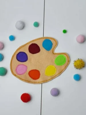 Palette de peinture en feutrine avec pastilles colorées et pompons pour jeu de tri des couleurs.