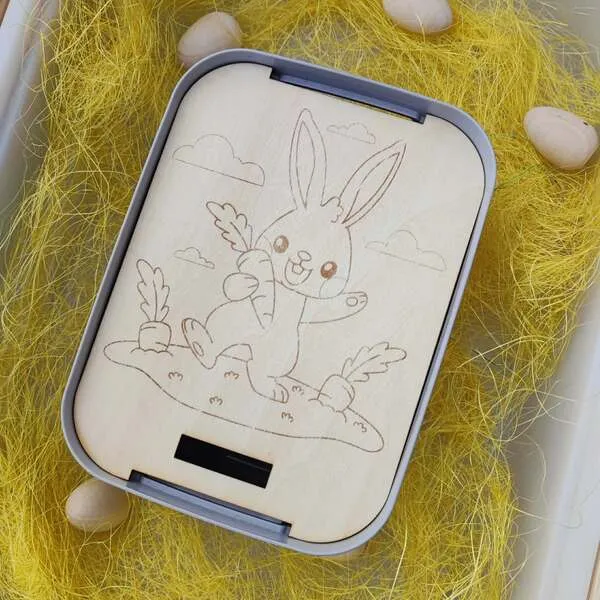 Insert en bois gravé lapin avec carotte dans un bac sensoriel de Pâques.