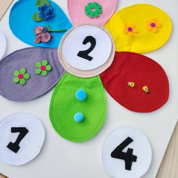 Détail fleur en feutrine colorée avec chiffre 2 et éléments à compter sur chaque pétale.