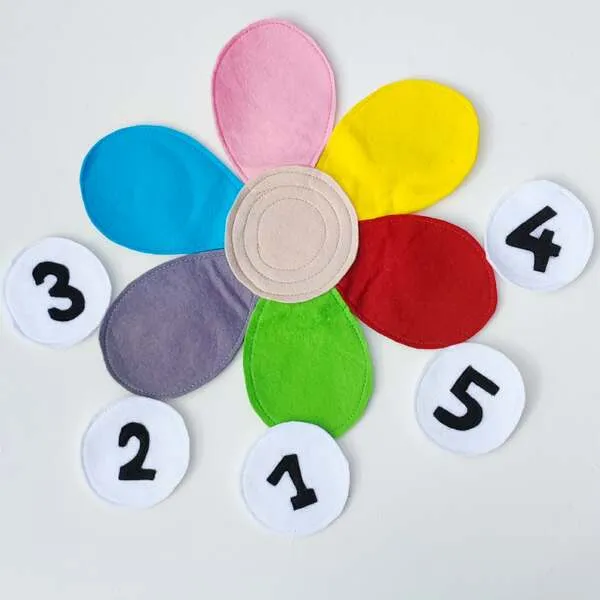 Fleur en feutrine colorée avec pétales vides et pastilles chiffres pour activité de dénombrement.