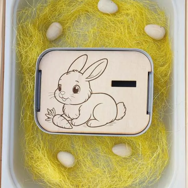 Insert en bois lapin avec carotte dans un bac sensoriel de Pâques.
