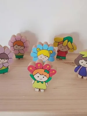 Figurines enfants en bois déguisés en fleurs colorées disposées pour jeu libre et mini monde printemps.