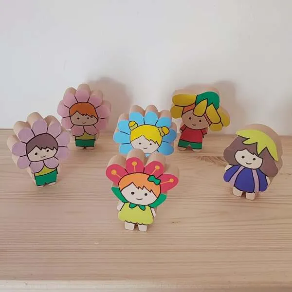 Figurines enfants en bois déguisés en fleurs colorées disposées pour jeu libre et mini monde printemps.