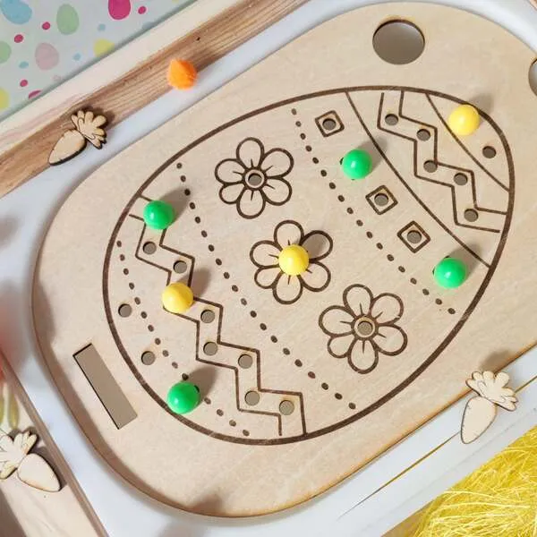 Insert sensoriel en bois gravé en forme d’œuf de Pâques avec pions colorés pour activité de motricité fine.