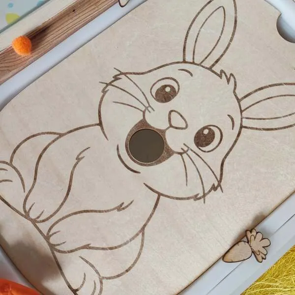 Insert sensoriel en bois gravé avec un lapin pour activité de Pâques dans une table sensorielle enfant.