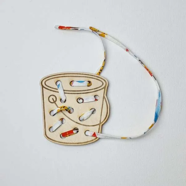 Carte à lacer tambour en bois avec lacet pour activité de motricité fine enfant.