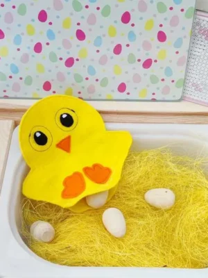 Poussin en feutrine avec poche sensorielle contenant des œufs en bois.