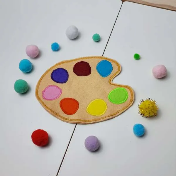 Palette de peinture en feutrine avec emplacements colorés et pompons pour activité de tri.