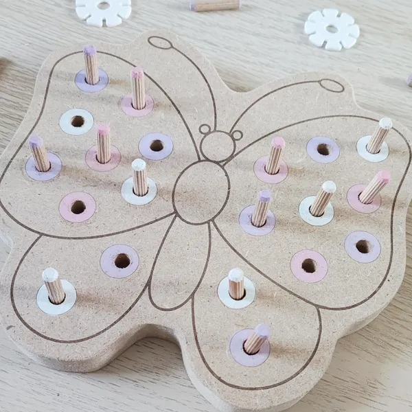 Détail plateau pic papillon en bois avec pions pour activité de motricité fine enfant.
