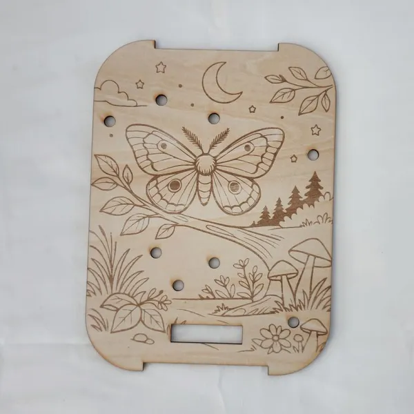 Plateau pic papillon de nuit en bois gravé avec lune, étoiles et décor de forêt pour activité de motricité fine enfant.