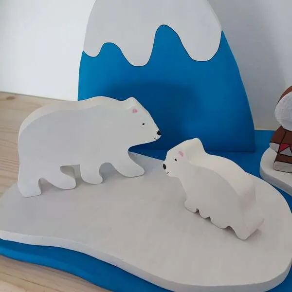 Figurines ours polaires en bois sur banquise avec montagne enneigée.