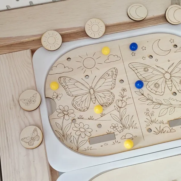 Détail insert papillon jour nuit en bois pour table sensorielle Flisat avec pions colorés.