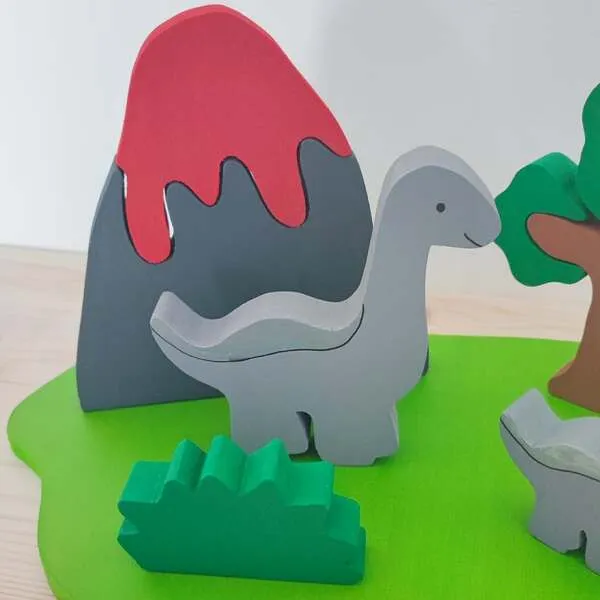 Figurine dinosaure en bois devant un volcan et décor nature.