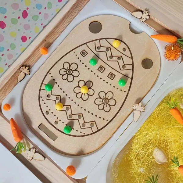 Insert sensoriel en bois en forme d’œuf de Pâques avec pions colorés pour activité de motricité fine enfant.
