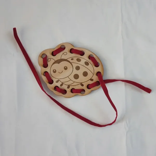Carte à lacer coccinelle en bois avec lacet rouge activité motricité fine enfant