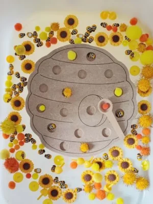 Plateau pompon ruche avec cuillère dans bac sensoriel thème abeille
