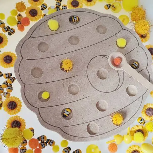 Plateau pompon ruche en bois avec cuillère et pompons dans activité sensorielle abeille