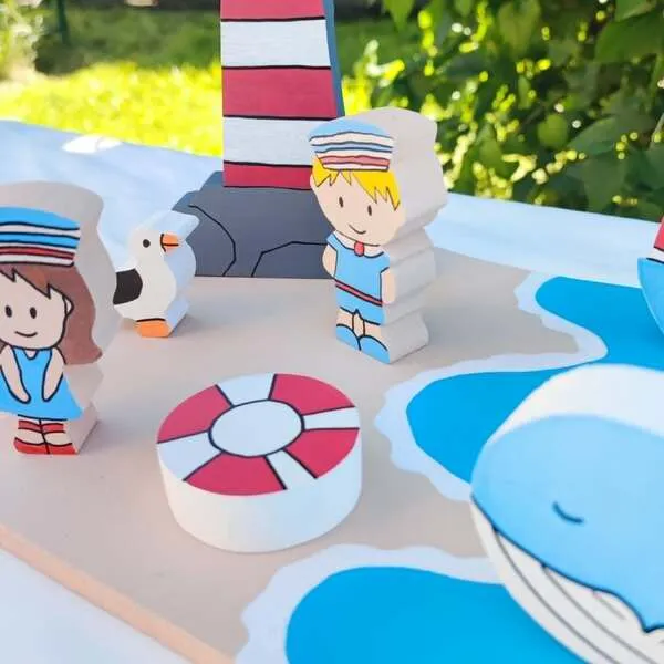 Détails d’un mini monde marin en bois avec personnages, mouette, phare, bouée et baleine