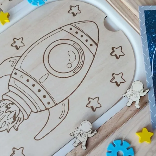 Insert en bois représentant une fusée entourée d'étoiles sur le thème de l'espace, adapté aux activités de motricité fine.