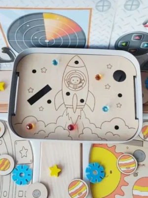 Insert en bois pour bac Livv 2L représentant une fusée en plein décollage avec un astronaute à bord et des emplacements à compléter.