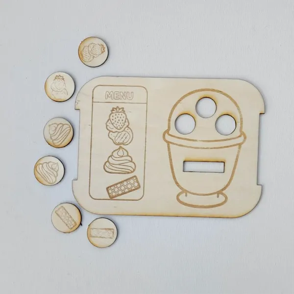 Insert Trofast en bois sur le thème de la glace, accompagné de jetons représentant les ingrédients nécessaires pour composer une coupe glacée selon le modèle proposé.