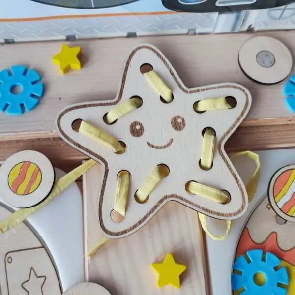 Carte à lacets en bois en forme d'étoile souriante avec ruban jaune pour travailler la motricité fine.