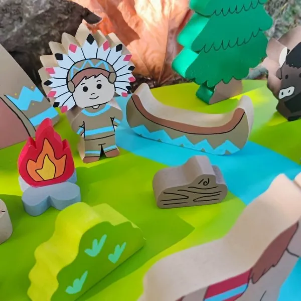 Gros plan sur le mini monde en bois des Indiens d'Amérique avec personnage, canoë, feu de camp, arbre, rivière et accessoires, dans un décor naturel.
