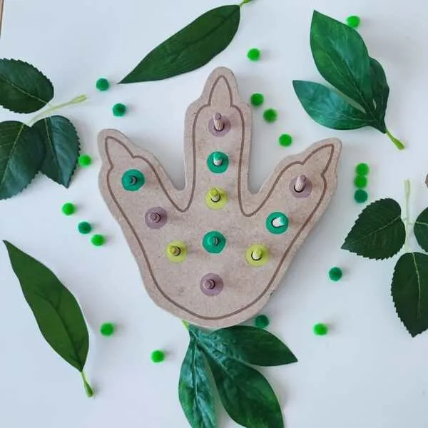 Plateau à pics en bois en forme d'empreinte de dinosaure avec pics et anneaux colorés pour développer la motricité fine des enfants.