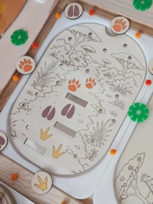 Plateau éducatif en bois sur le thème de la savane représentant un chemin avec différentes empreintes d'animaux. Les enfants observent puis associent les jetons correspondant aux empreintes du lion, de la girafe et de l'hippopotame. Cette activité Montessori développe la discrimination visuelle, l'observation, la logique, la motricité fine et la découverte des animaux sauvages. Adapté aux assistantes maternelles, MAM, crèches, écoles maternelles et familles.