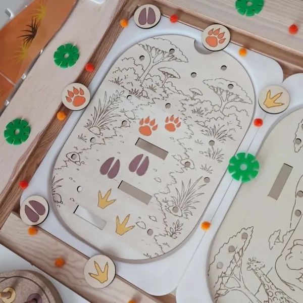 Plateau éducatif en bois sur le thème de la savane représentant un chemin avec différentes empreintes d'animaux. Les enfants observent puis associent les jetons correspondant aux empreintes du lion, de la girafe et de l'hippopotame. Cette activité Montessori développe la discrimination visuelle, l'observation, la logique, la motricité fine et la découverte des animaux sauvages. Adapté aux assistantes maternelles, MAM, crèches, écoles maternelles et familles.