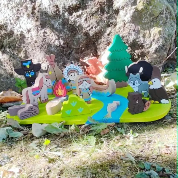 Mini monde en bois sur le thème des Indiens d'Amérique installé en extérieur avec personnages, tipi, canoë, animaux, feu de camp et rivière pour favoriser le jeu libre.