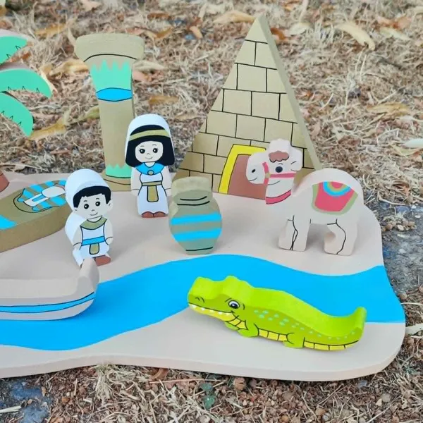 Gros plan sur le mini monde en bois Égypte avec pyramide, colonne, personnages, chameau, vase, crocodile et rivière, présenté en extérieur.