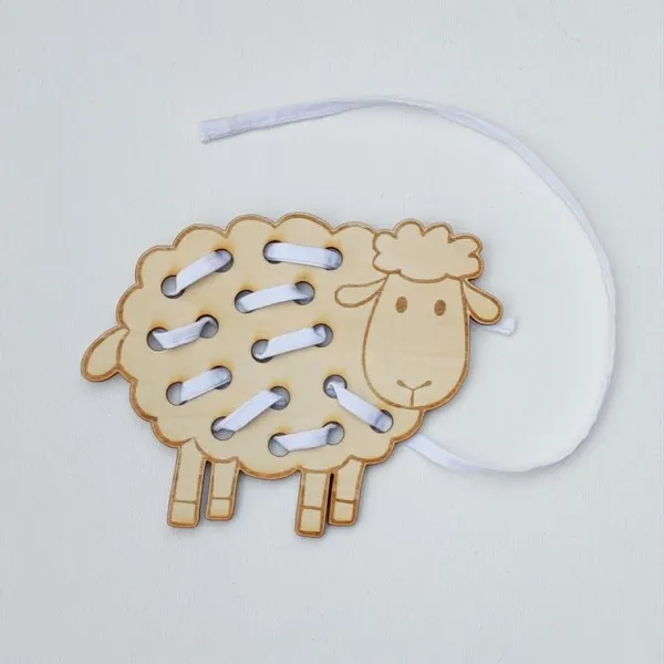 Carte à lacer en bois en forme de mouton avec un lacet blanc partiellement enfilé pour représenter sa toison.