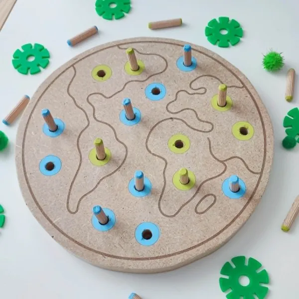 Plateau de motricité en bois représentant la planète Terre avec des pics colorés à placer dans les emplacements correspondants.