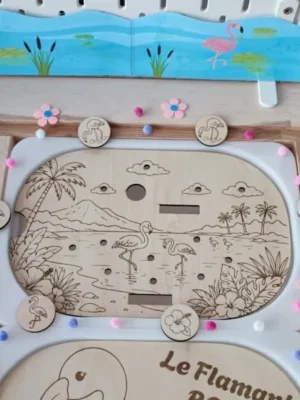 Insert Livv 2L en bois sur le thème du flamant rose représentant un paysage tropical gravé. L'enfant retrouve les flamants roses et les fleurs d'hibiscus sur les jetons pour les associer aux bons emplacements dans le décor.
