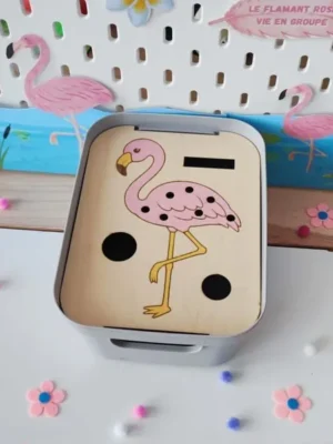 Insert en bois pour bac Livv 2L représentant un flamant rose coloré, avec des emplacements pour insérer des plumes. Le support est présenté dans un bac gris au sein d'une décoration sur le thème tropical.