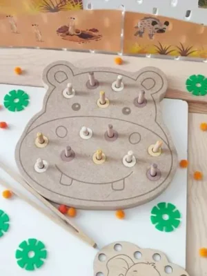 Plateau de motricité fine en MDF en forme d'hippopotame avec des chevilles en bois colorées à insérer et retirer. Cette activité développe la coordination œil-main, la précision des gestes, la logique et la motricité fine des jeunes enfants.