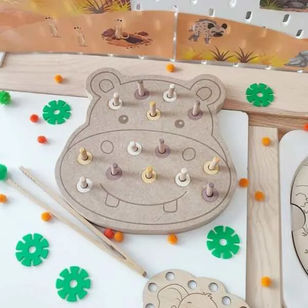 Plateau de motricité fine en MDF en forme d'hippopotame avec des chevilles en bois colorées à insérer et retirer. Cette activité développe la coordination œil-main, la précision des gestes, la logique et la motricité fine des jeunes enfants.