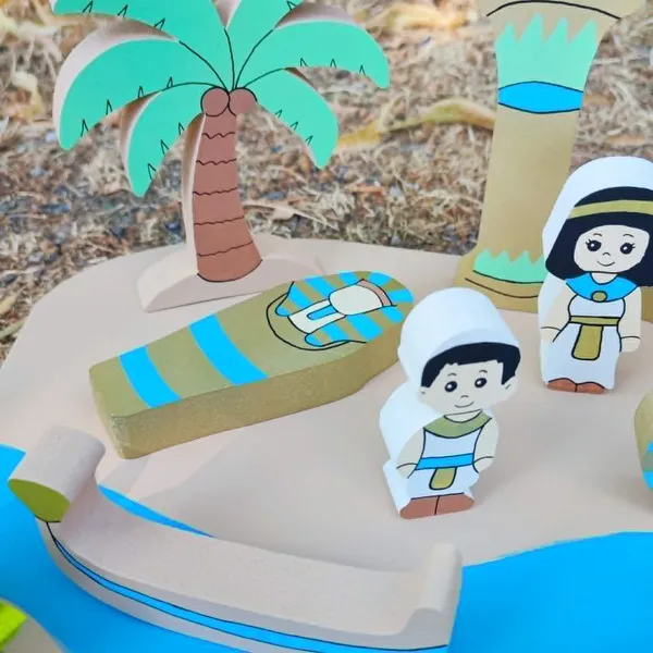 Gros plan sur le mini monde en bois Égypte montrant un palmier, un sarcophage, une barque, une colonne et deux personnages égyptiens peints à la main.