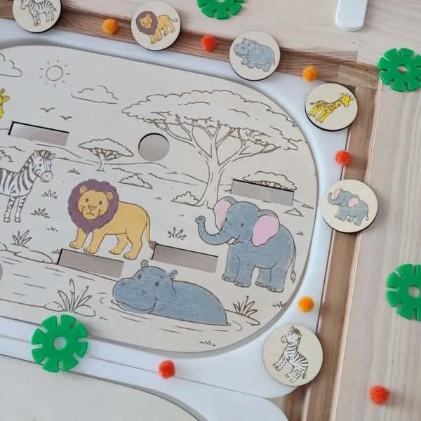 Gros plan sur un plateau éducatif en bois représentant la savane avec un lion, un éléphant, un hippopotame et un zèbre. Les enfants doivent associer les jetons illustrés aux bons animaux et compléter les emplacements. Cette activité Montessori développe le vocabulaire, la reconnaissance des animaux, l'observation, la motricité fine et la concentration. Idéal pour les assistantes maternelles, MAM, crèches, écoles maternelles et familles.