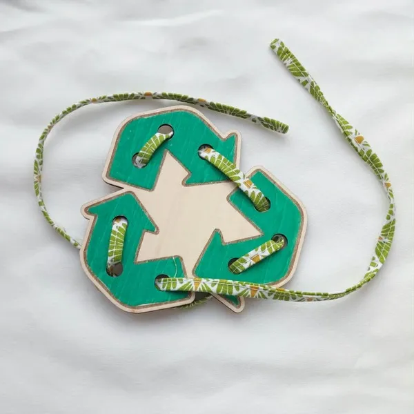 Carte à lacer en bois représentant le symbole du recyclage avec un lacet en tissu.