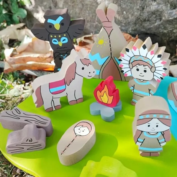 Gros plan sur le mini monde en bois des Indiens d'Amérique avec tipi, totem, cheval, feu de camp, personnages, bébé emmailloté et accessoires, présenté dans un décor naturel
