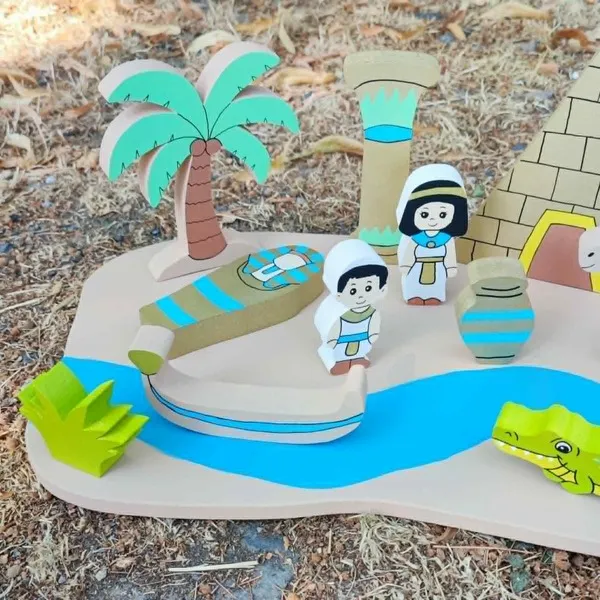 Gros plan sur le mini monde en bois Égypte avec personnages, barque, palmier, colonne, pyramide, vase, crocodile et rivière, présenté en extérieur.
