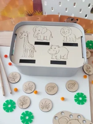 Insert en bois pour bac sensoriel LIVV 2L sur le thème de la savane. Cette activité de tri invite l'enfant à associer chaque animal à son alimentation grâce à des jetons en bois représentant de l'herbe, des feuilles et de la viande. Jeu éducatif Montessori favorisant la motricité fine, le raisonnement logique, le vocabulaire et la découverte des animaux sauvages.