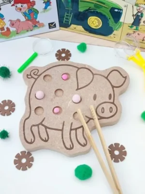 Plateau en bois en forme de cochon avec emplacements pour pompons, accompagné d'une pince en bois.