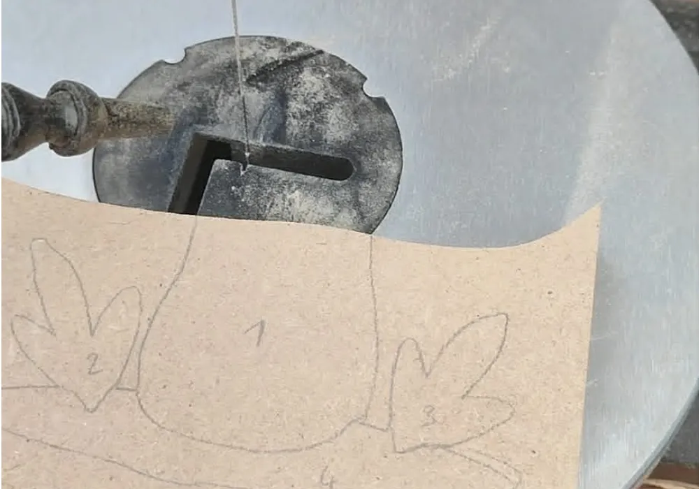 Découpe d'une création en bois à la scie à chantourner à partir d'un dessin tracé sur le support.