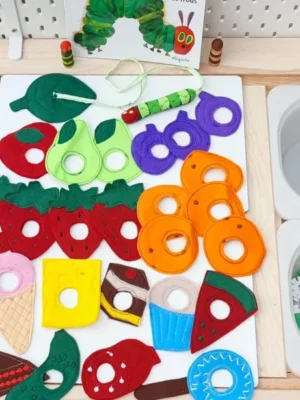 Jeu en feutrine inspiré de La chenille qui fait des trous avec une chenille à nourrir et de nombreux aliments colorés (fruits, légumes, desserts et gourmandises).