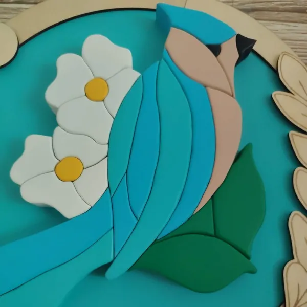 Détail d’un cadre décoratif en bois avec oiseau bleu et fleurs blanches en relief