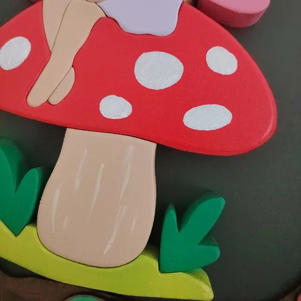 Détail d’une fée assise sur un champignon rouge en bois peint et assemblé en relief
