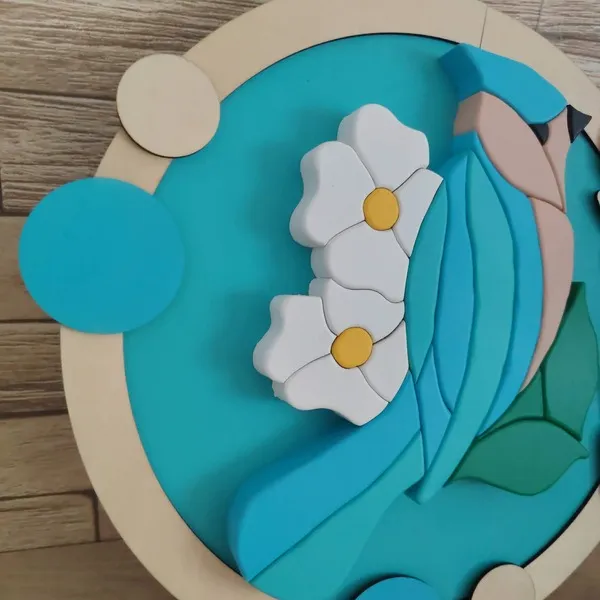 Détail d’un cadre décoratif en bois avec oiseau bleu et fleurs blanches en relief